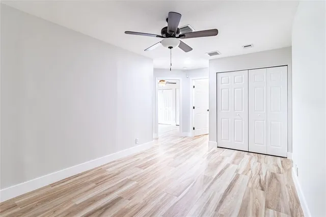 a view of empty room with wooden floor and ceiling fan