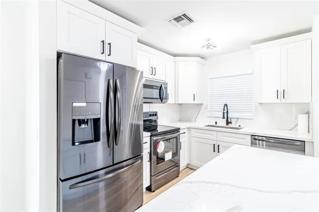 a kitchen with stainless steel appliances a refrigerator sink and cabinets
