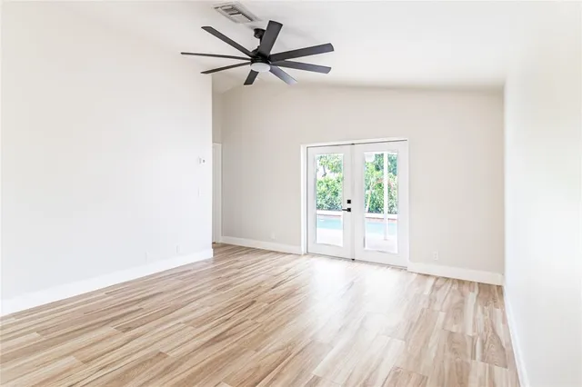 a view of an empty room with wooden floor and a window
