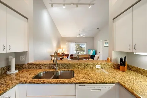 a kitchen with granite countertop a sink a stove and cabinets