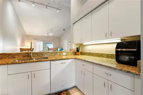 a kitchen with granite countertop white cabinets and white appliances