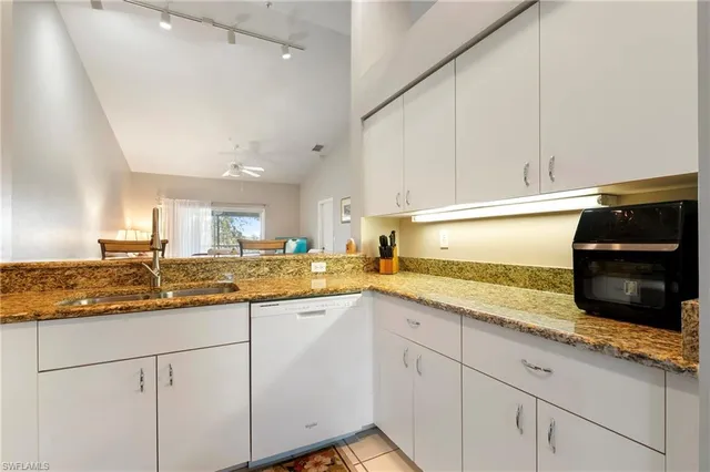 a kitchen with granite countertop white cabinets and white appliances