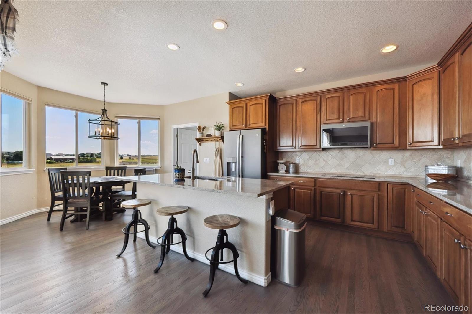 724 Imboden Road Watkins, CO 80137 - Photo 11 of 50 a kitchen with sink a refrigerator and chairs