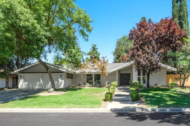 a front view of a house with a yard and potted plants