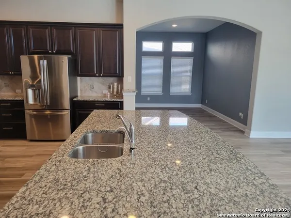 a kitchen with kitchen island granite countertop a refrigerator and a sink