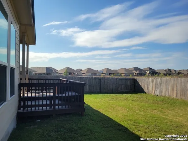 a view of a big yard with a lake view and wooden fence