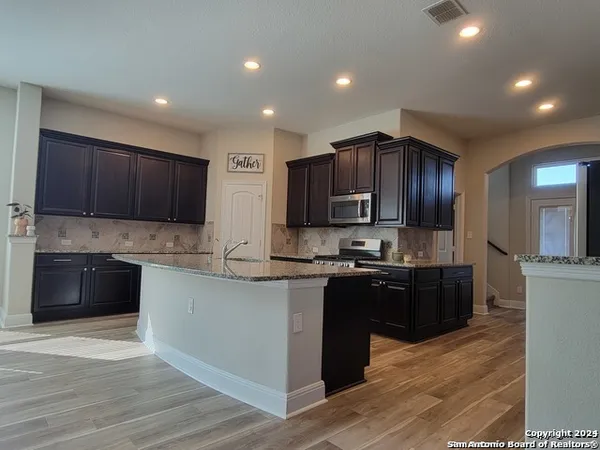 a kitchen with stainless steel appliances granite countertop wooden cabinets a refrigerator and a stove top oven