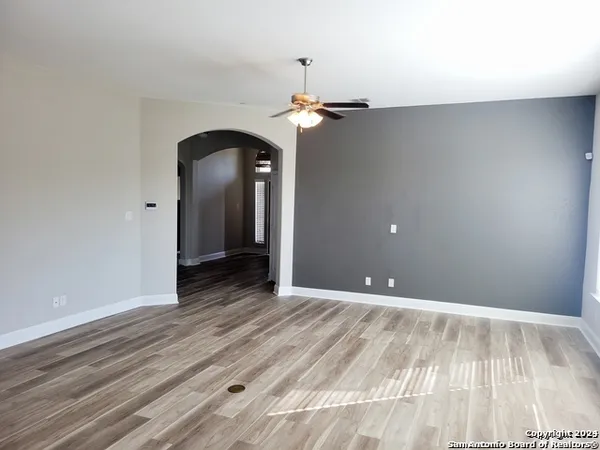 a view of empty room with wooden floor and ceiling fan