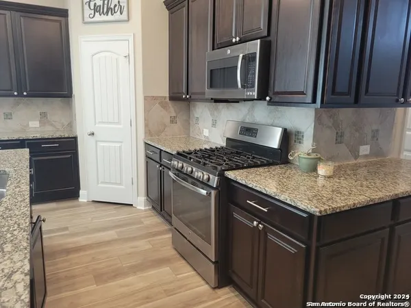 a kitchen with stainless steel appliances granite countertop a stove microwave and refrigerator