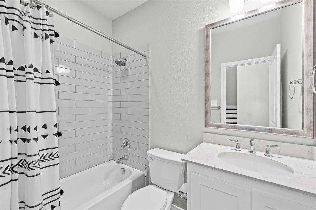 437 Prairie Run Aledo, TX 76008 - Photo 13 of 33 Bathroom featuring a white subway tile shower surround, a built-in bathtub with chrome fixtures, a single vanity with an integrated sink, a light-colored countertop, and a framed mirror