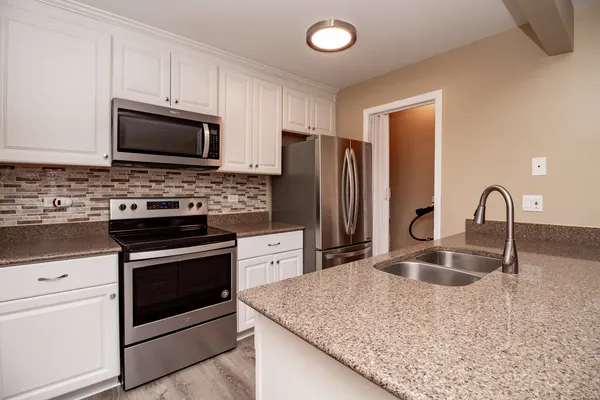 a kitchen with stainless steel appliances granite countertop a stove microwave and refrigerator