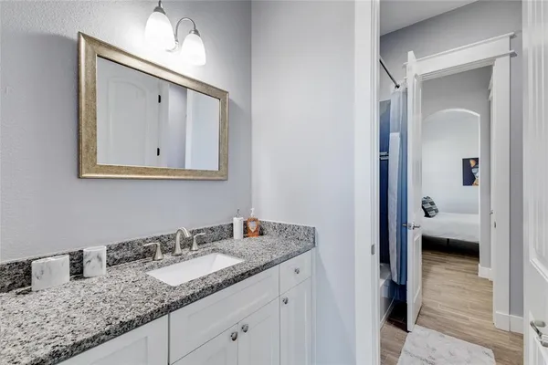 a en suite bathroom with a granite countertop sink and a mirror