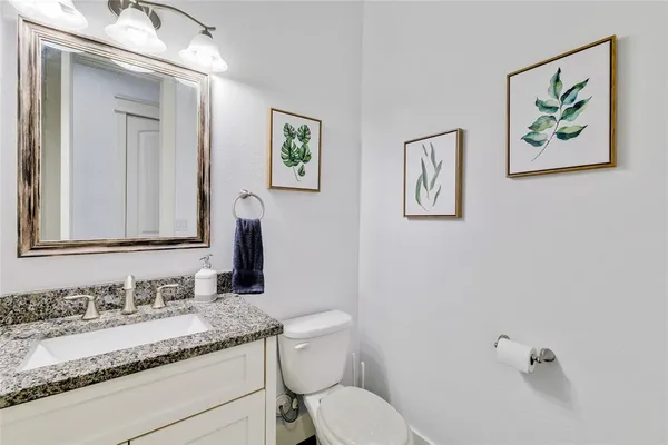a bathroom with a granite countertop sink mirror vanity and toilet