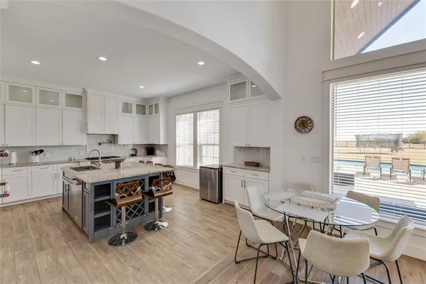 a kitchen with a stove a sink a kitchen island with chairs and wooden floor