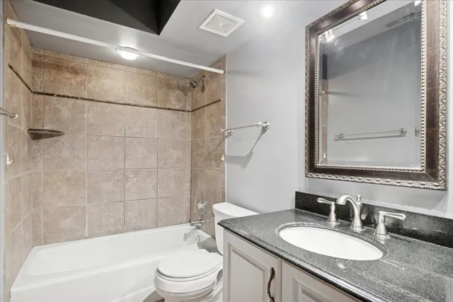 a bathroom with a granite countertop sink mirror toilet and bathtub