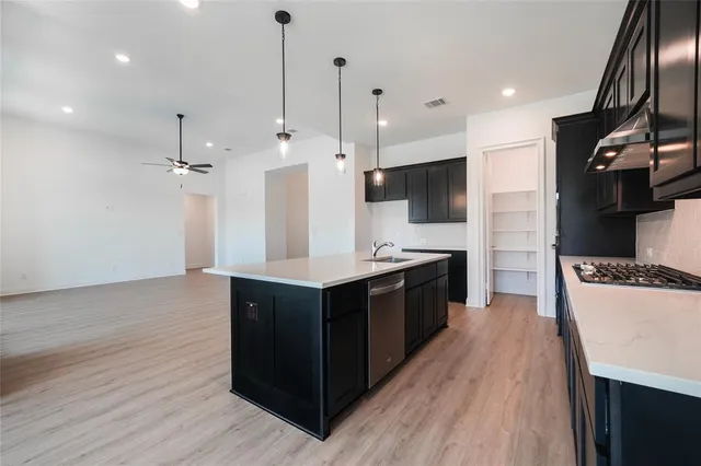 a large kitchen with stainless steel appliances a large counter top a stove a sink and a refrigerator