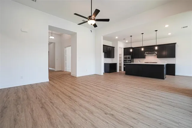 a view of empty room with wooden floor and a ceiling fan