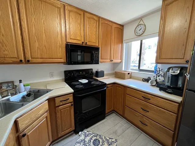a kitchen with granite countertop cabinets stainless steel appliances a sink and window