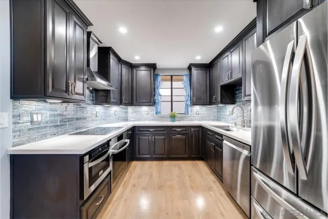 a kitchen with stainless steel appliances granite countertop a sink a stove and a refrigerator