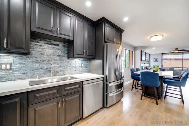 a kitchen with stainless steel appliances granite countertop a sink stove refrigerator dining table and chairs