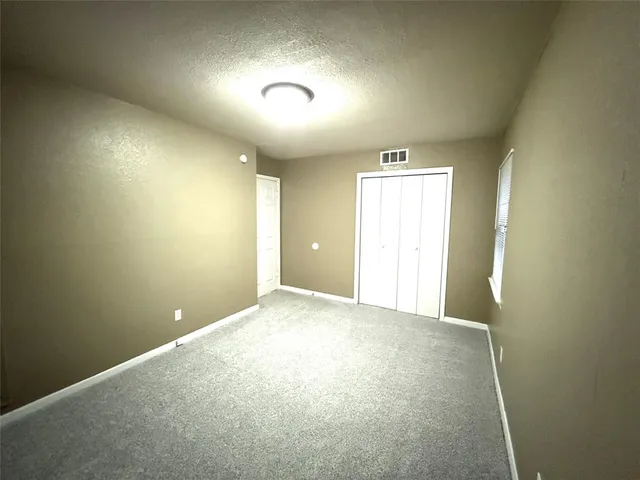 an empty room with closet and windows