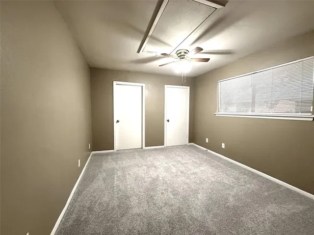 an empty room with chandelier fan and windows