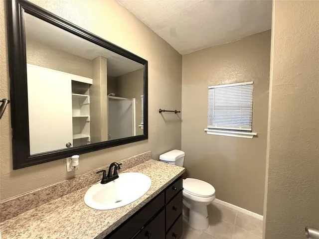 a bathroom with a granite countertop sink toilet and mirror