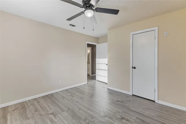 an empty room with wooden floor a ceiling fan and closet