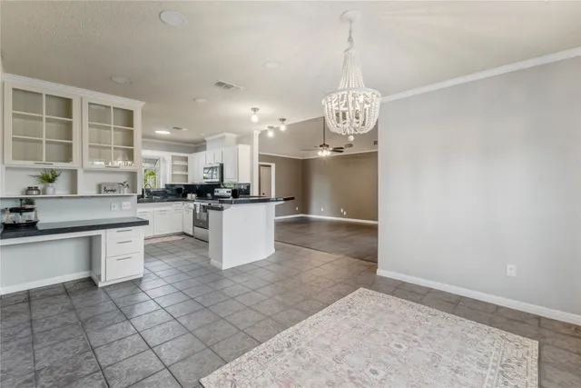 a large white kitchen with a refrigerator a stove a sink and a chandelier