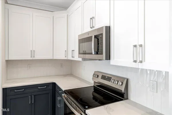 a kitchen with a stove and white cabinets