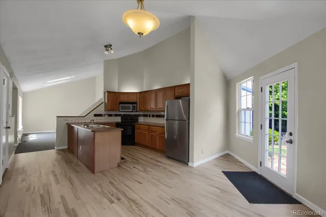a kitchen with granite countertop a refrigerator stove and wooden floor