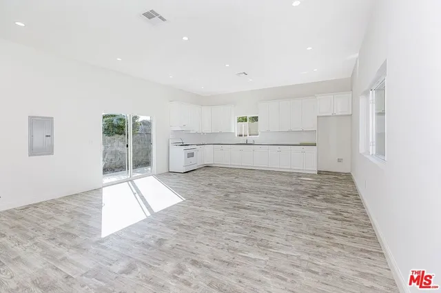 a large white kitchen with kitchen island a sink stainless steel appliances and cabinets