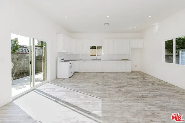 a large white kitchen with kitchen island a sink stainless steel appliances and cabinets
