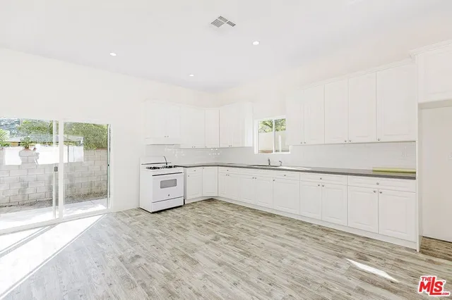 a kitchen with granite countertop a sink cabinets and stainless steel appliances