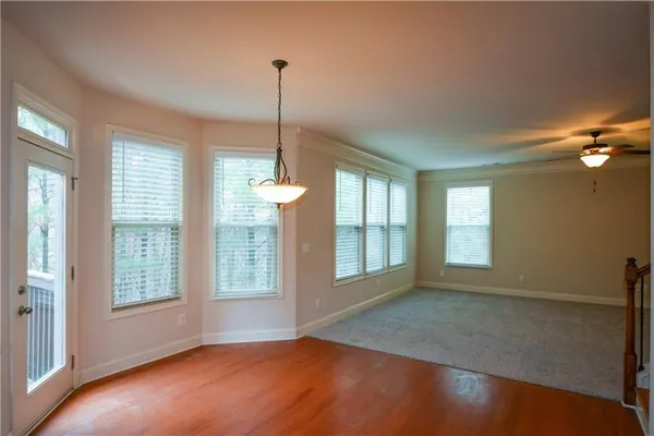 a view of an empty room with a window and wooden floor