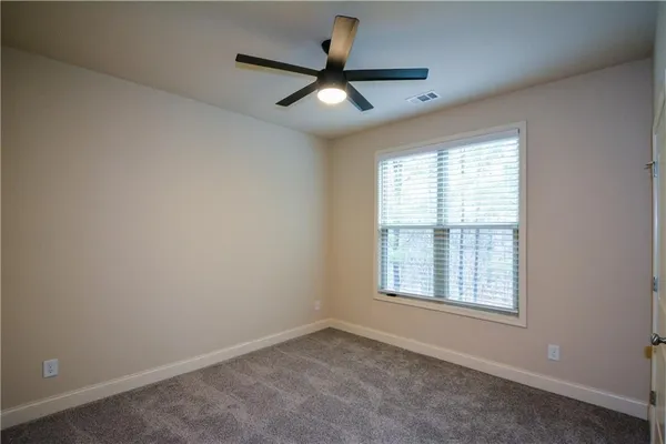 an empty room with ceiling fan and windows