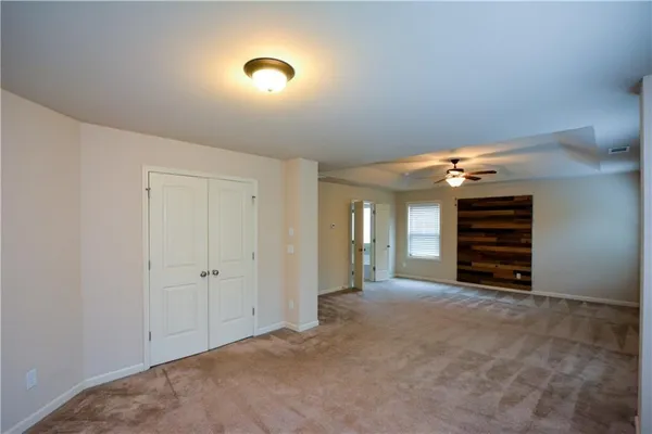 a view of an empty room with closet and a window