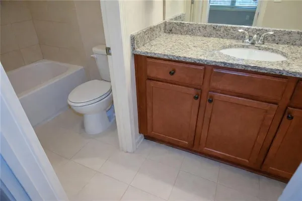 a bathroom with a granite countertop sink a toilet and bathtub