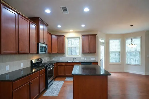 a kitchen with stainless steel appliances granite countertop a sink a stove and a refrigerator