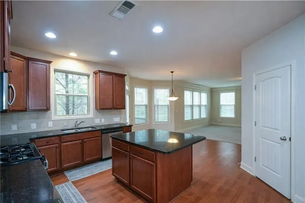 a large kitchen with kitchen island a sink dishwasher a stove and a refrigerator with wooden floor
