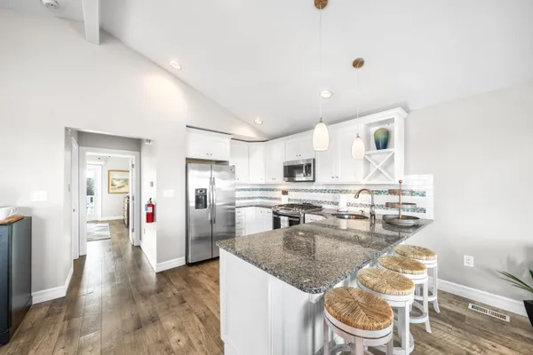 a kitchen with granite countertop a sink a stove and a wooden floor