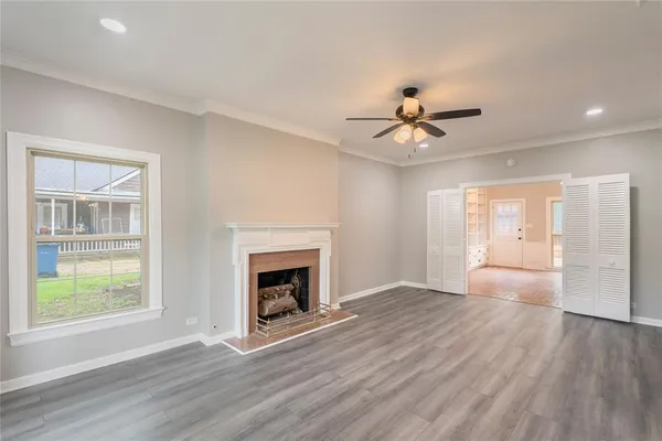 an empty room with chandelier fan and wooden floor
