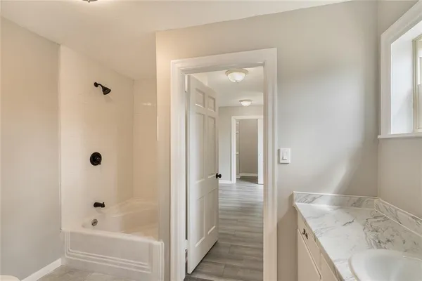 a bathroom with a granite countertop sink a mirror a bathtub and shower