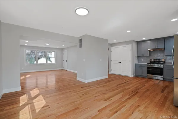 a view of empty room with kitchen and window