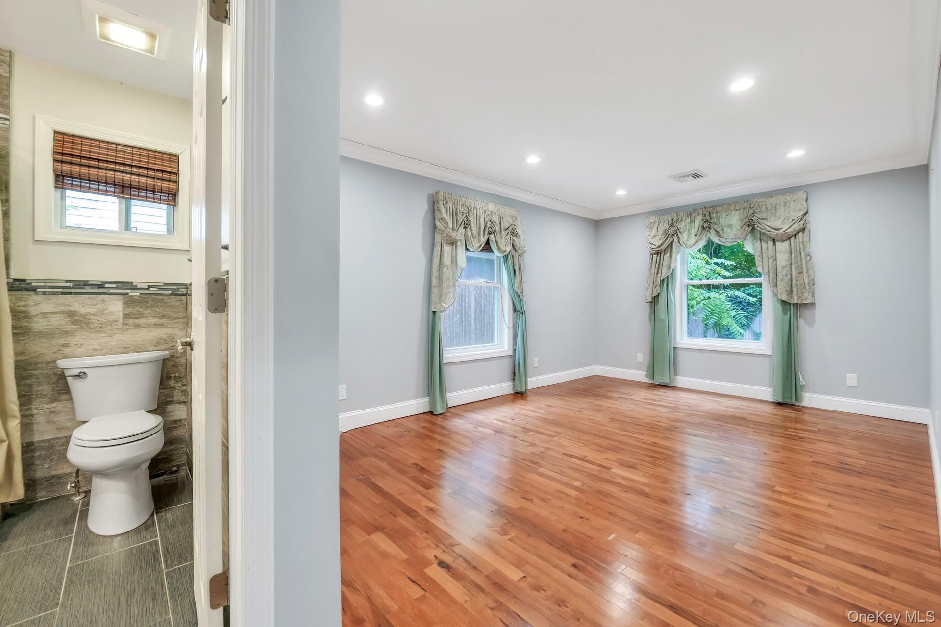 30 Harding Road Ronkonkoma, NY 11779 - Photo 22 of 38 a view of a hallway with wooden floor and a bathroom