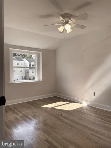an empty room with wooden floor chandelier fan and windows
