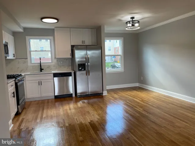 a kitchen with stainless steel appliances a sink cabinets and wooden floor