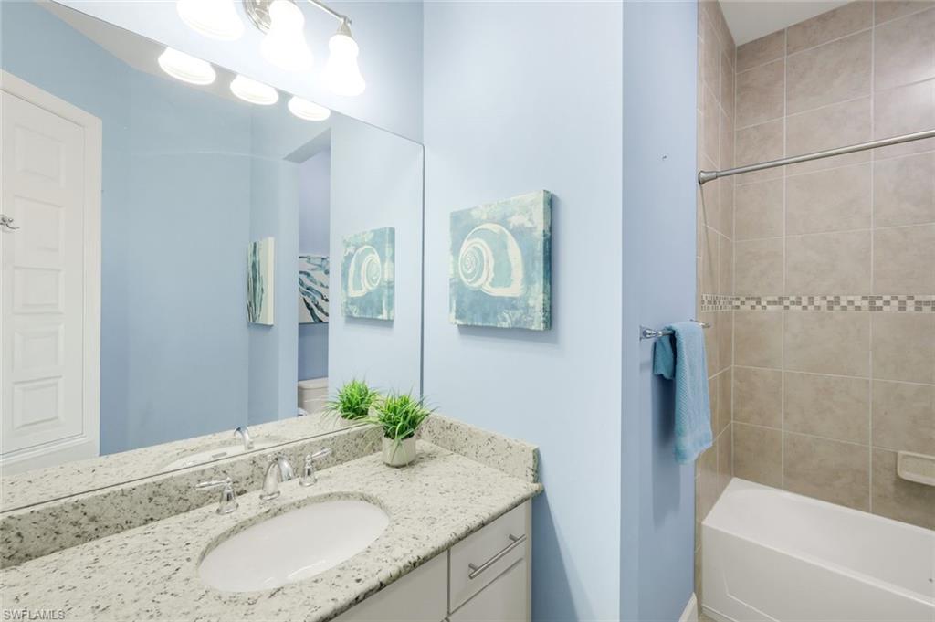 9314 Quarry Drive Naples, FL 34120 - Photo 24 of 49 a bathroom with a granite countertop sink a mirror and a bathtub