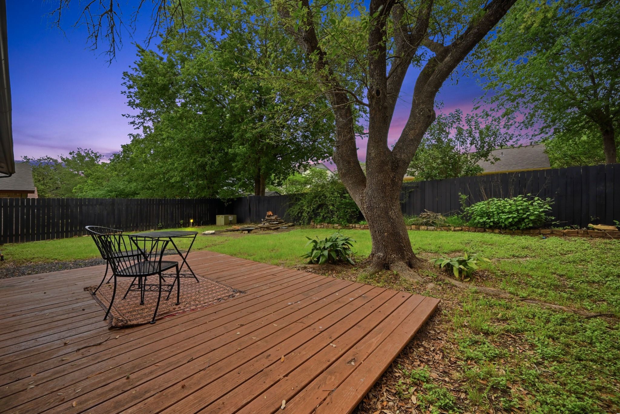 6805 Rearden Road Austin, TX 78745 - Photo 21 of 26 A tranquil backyard retreat features a wooden deck and lush green lawn, ideal for outdoor relaxation.