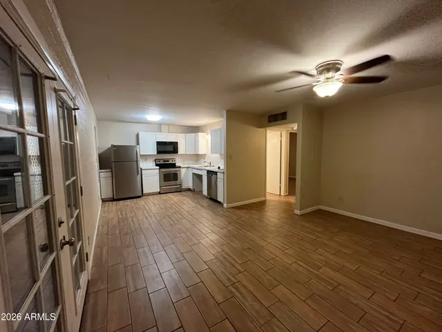 a view of empty room with wooden floor and ceiling fan